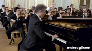 Daniel Barenboim playing piano while conducting.